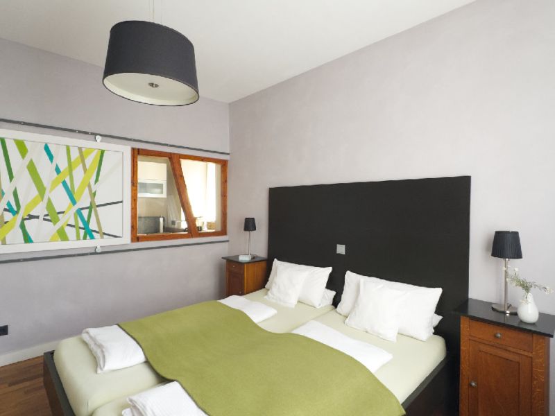 Schlafzimmer 1 mit Doppelbett und Blick zum Innenfenster der Küche