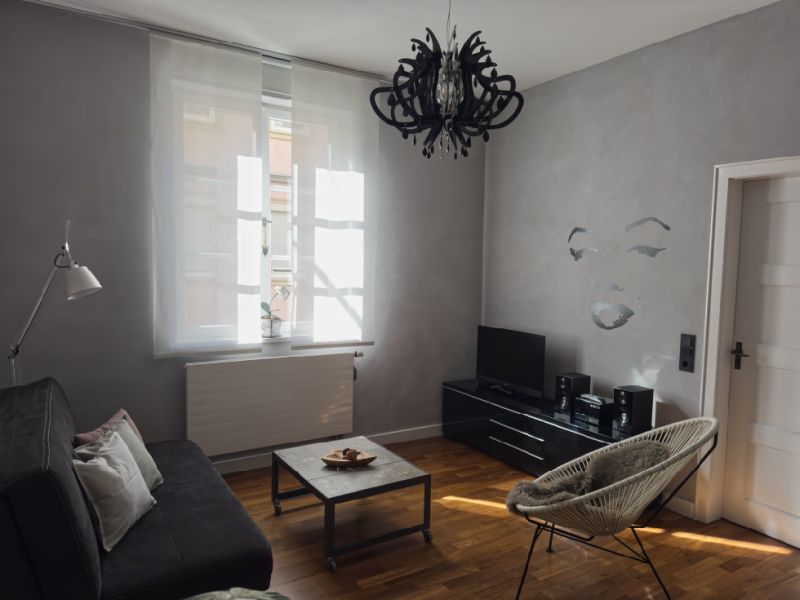 Helles Wohnzimmer mit Sofa, Sessel, Fernseher und Parkettboden