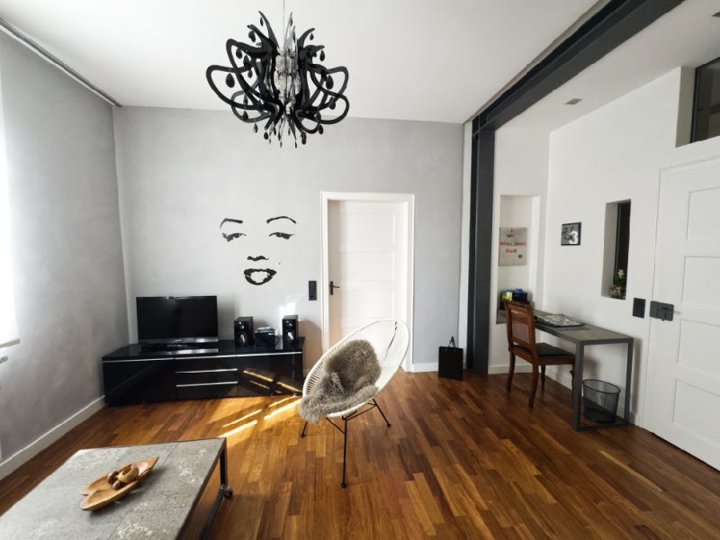 Wohnzimmer mit Fernseher, Sessel, Schreibtisch und Parkettboden